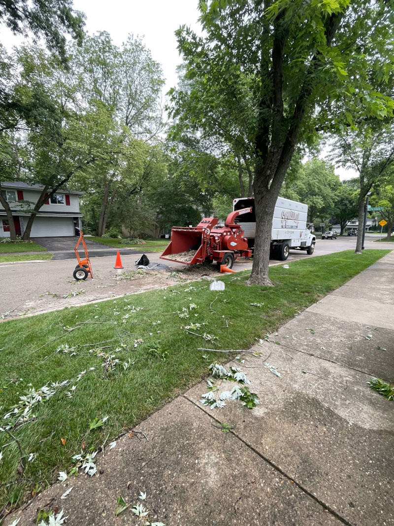 Wide view of chipper truck and equipment on a tree-lined street